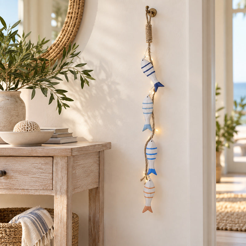 Blue, white and coral LED fish garland hanging vertically beside a coastal timber console.