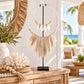 Decorative cuttlefish shell necklace with white shells, natural wooden beads and ivory hanging accents, displayed on a black metal stand atop a timber console in a coastal-style home.