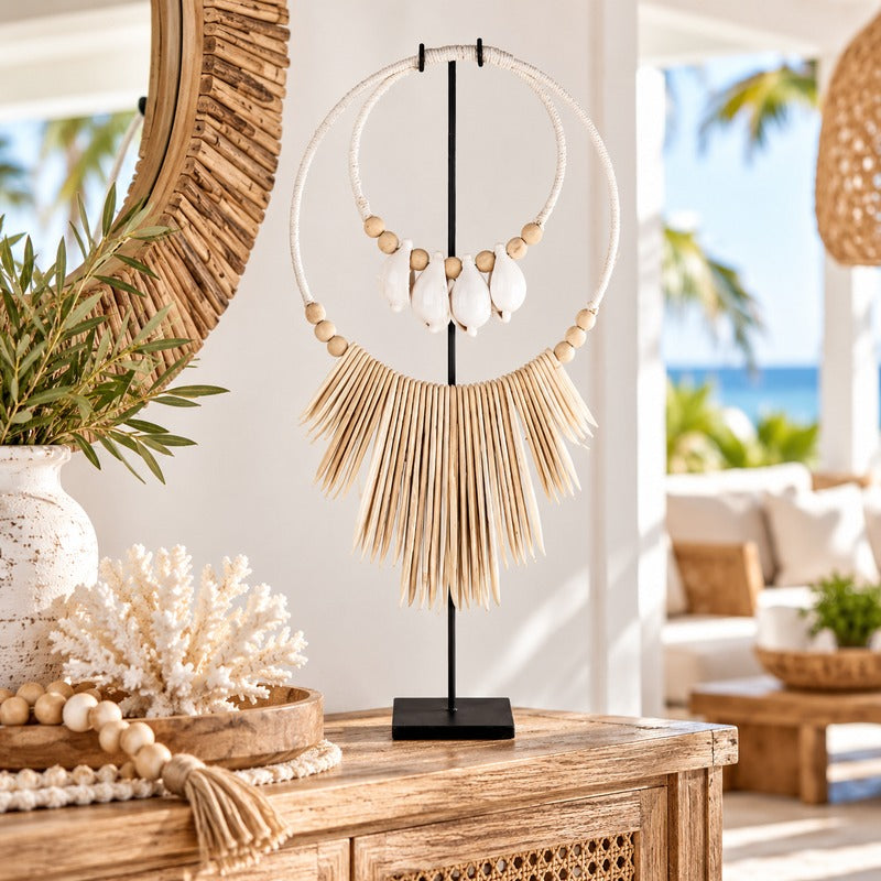 Decorative cuttlefish shell necklace with white shells, natural wooden beads and ivory hanging accents, displayed on a black metal stand atop a timber console in a coastal-style home.
