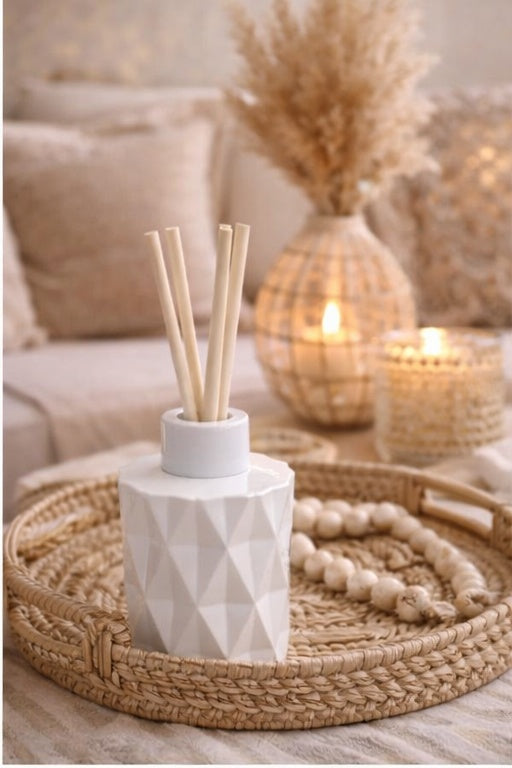 Decorative diffuser with reeds on a woven tray in a cozy living room setting.