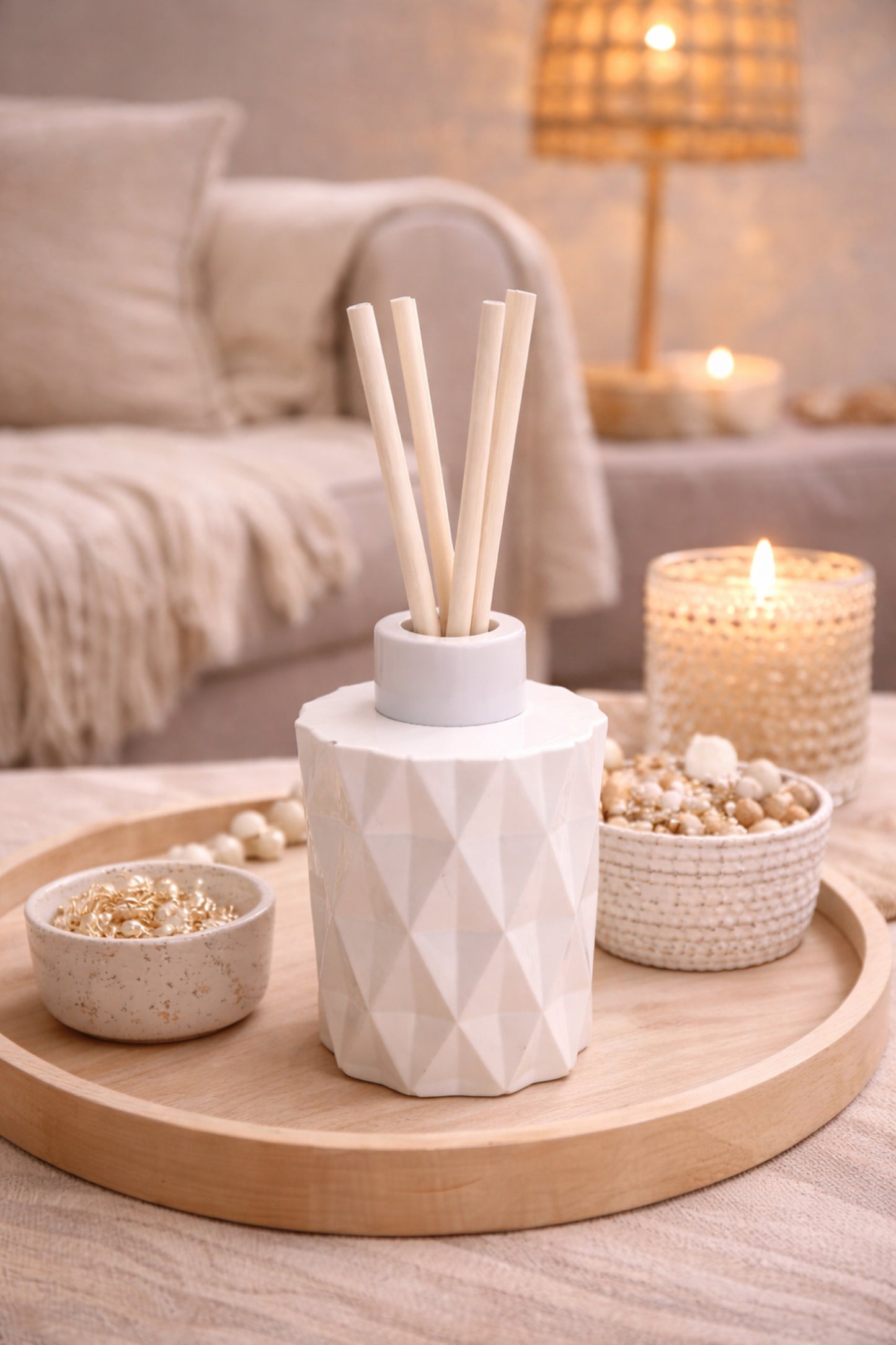 Decorative diffuser with sticks on a wooden tray in a cozy living room setting.