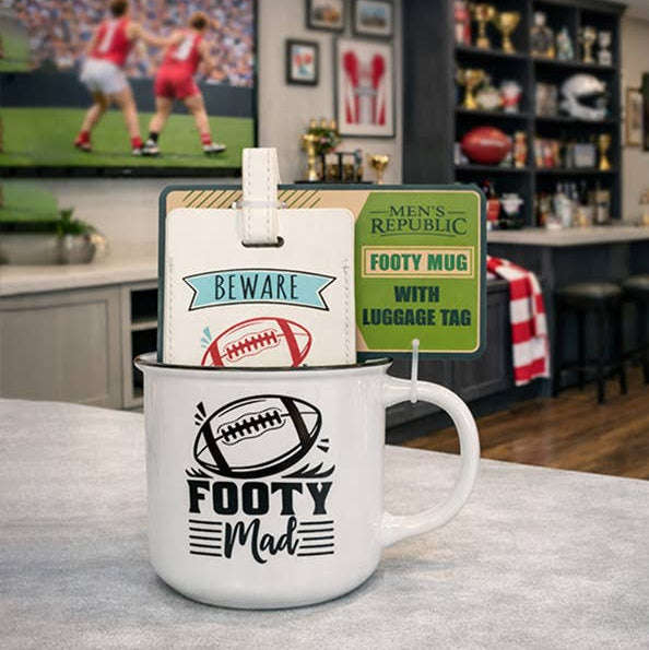 White mug with 'Footy Mad' design on a table, with packaging labeled 'Men's Republic' in the background.