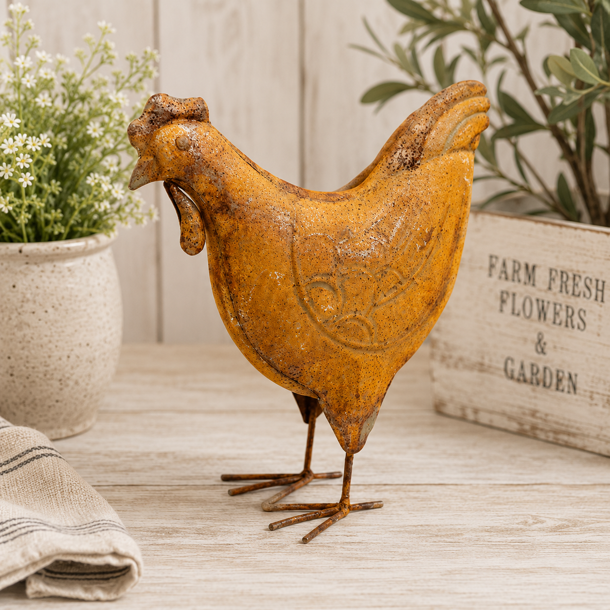 Rust-colored chicken sculpture on a wooden surface with plants in the background