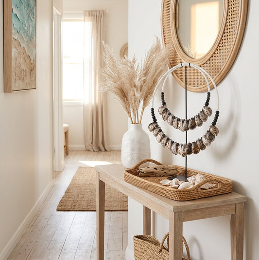 A double-strand statement necklace featuring natural cowrie shells with brown spots on a white and black cord, displayed on a black stand against a white background.