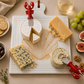 Lobster knives on a shell trivet with assorted cheeses , crackers, grapes, and figs.