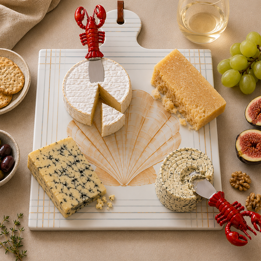 Lobster knives on a shell trivet with assorted cheeses , crackers, grapes, and figs.