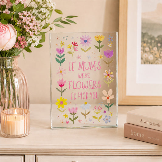 Decorative glass panel with floral design and text on a table with flowers and books.
