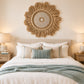 A circular woven wall hanging with a sunflower-inspired design, featuring a dense woven center, a ring of rope, and long frayed natural-fiber petals around the edge, shown on a plain white background.