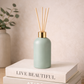 Green diffuser bottle on a stack of books with a neutral background