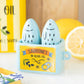 Sardine-shaped salt and pepper shakers in a container with a yellow label, surrounded by lemons.