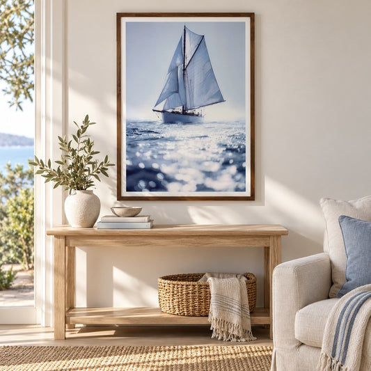 Solo Sailing framed artwork above a timber console in a coastal living room with a linen armchair and soft afternoon light.
