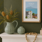 Decorative mantelpiece with vases, a pitcher, and a framed picture of Italy.